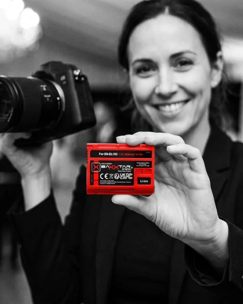 Hochzeitsfotografin hält Kamera und einen roten Baxxtar EN-EL15C-Akku für Nikon