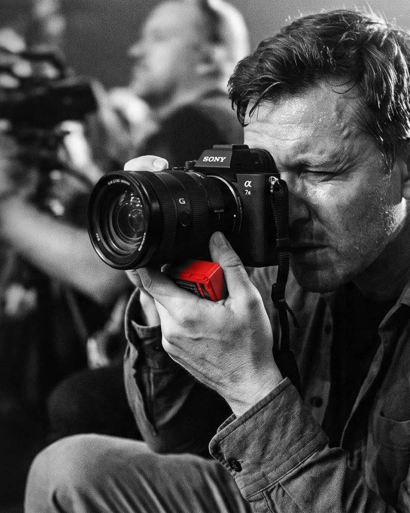Fotograf mit Kamera, darunter ein roter Baxxtar-Akku für Sony